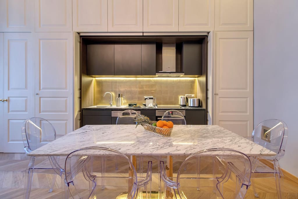 Integrated modern kitchen with built in appliances and a grand Calacata marble table.
