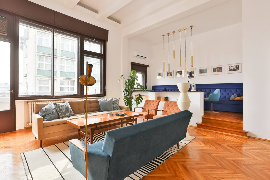 The spacious living room area, full of light, during day-time.