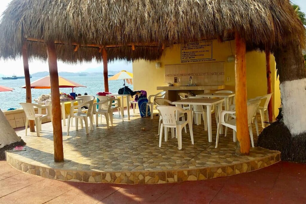 Palapa junto a la alberca con sillas y mesas