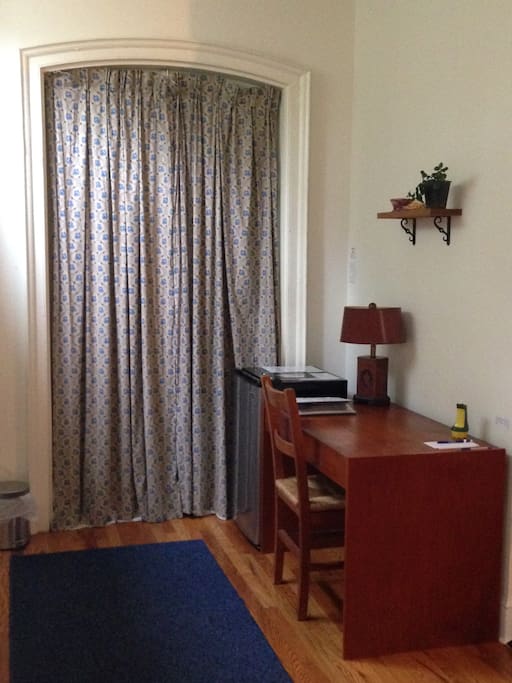 Writing nook and mini-fridge are just across from the door. A binder with information about shopping, travel, and more is on the desk.