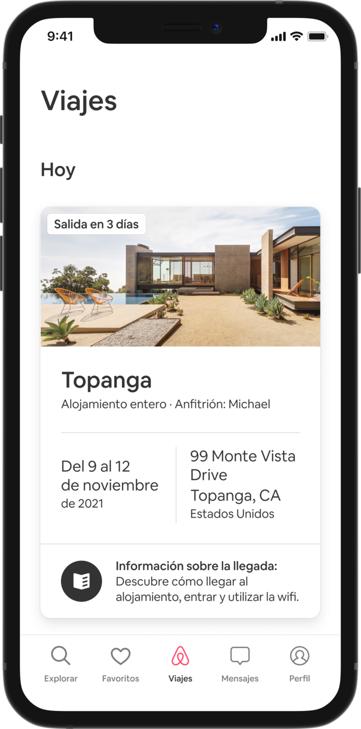 Un teléfono móvil muestra la pestaña Viajes de un huésped con su próxima estancia programada. Debajo de un encabezado que dice «Hoy», aparece una imagen de una casa de estilo alpino, y debajo están los detalles de la reserva del huésped: el título del anuncio, el nombre del anfitrión, la dirección y las fechas del viaje. En la parte inferior de la página, hay un botón que dice: «Tus datos de llegada. Descubre cómo llegar al alojamiento, entrar y utilizar el wifi».