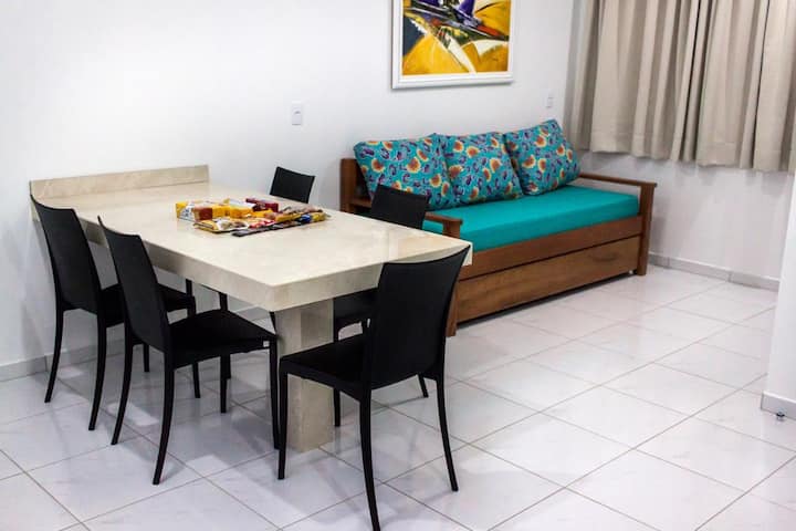 Habitación grande con 01 mesa, con 05 sillas, 01 sofá cama y 01 TV inteligente