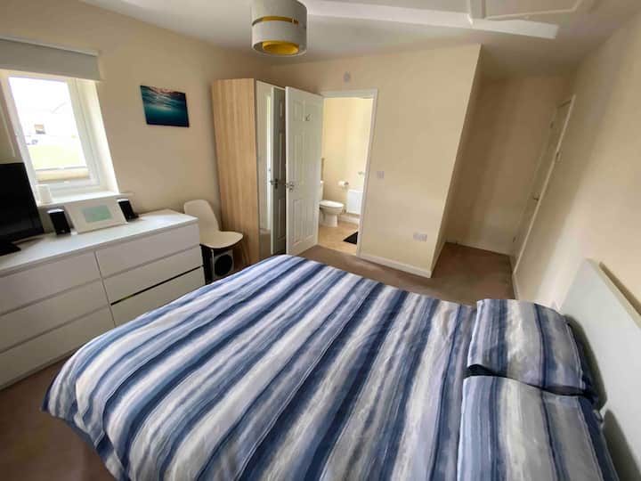 غرفة نوم رئيسية بسرير بمقاس كبير وغرفة استحمام داخلية.