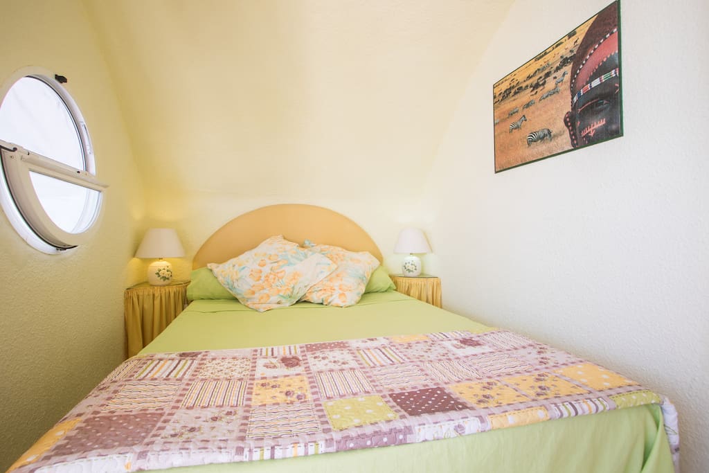 Double bed in alcove with opening round window.