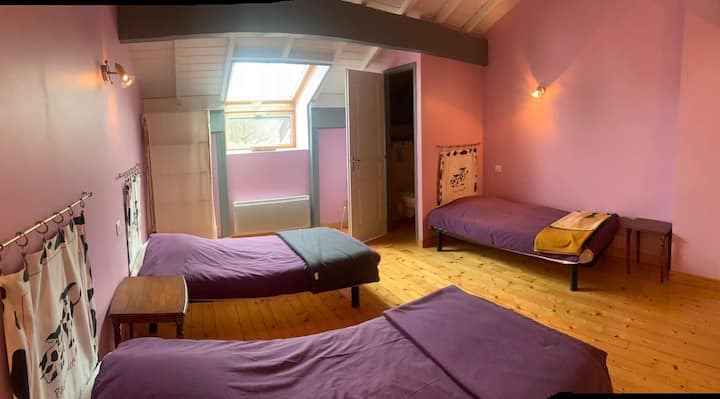 Dormitorio altillo con tres camas individuales y un aseo con lavabo.