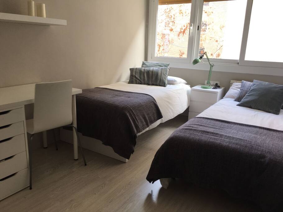 Habitación privada con dos camas, mesa escritorio y mucha luz