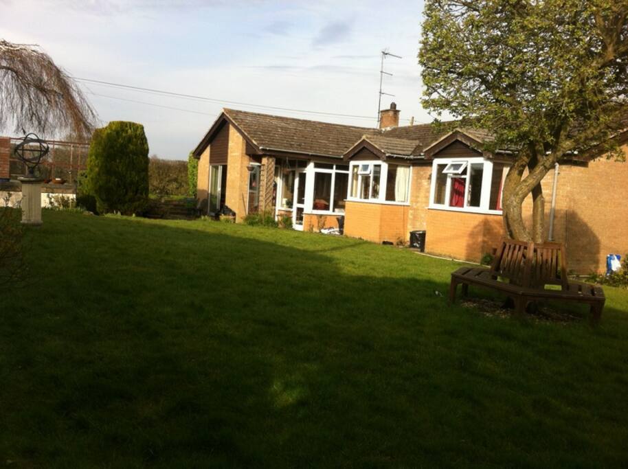Large bungalow, large garden. Bench under the tree.