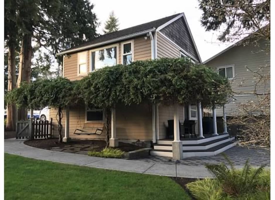 The building features a climbing clematis and hanging porch swing, outdoor furniture, and grill.