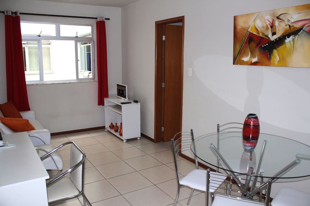 Sala de estar espaçosa com televisão, mesa e escrivaninha para trabalho e estudo.