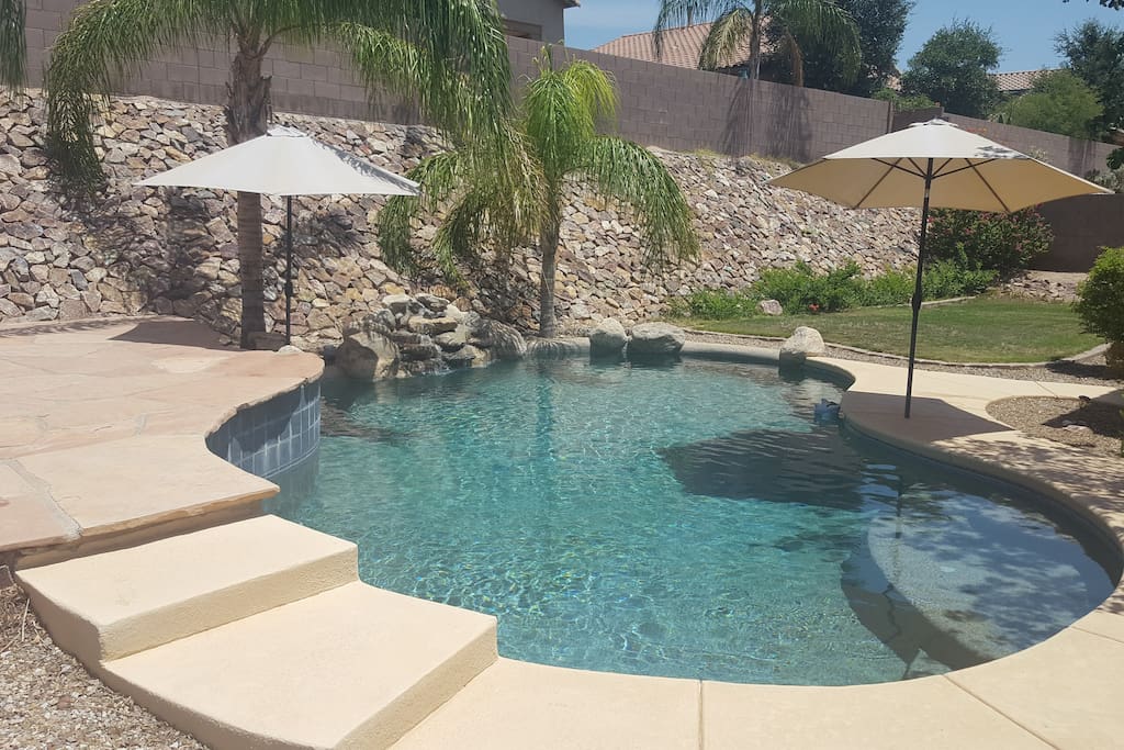 Peaceful and private pool with waterfalls, sundeck, umbrellas, and palm trees