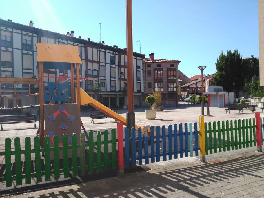 Plaza peatonal con juegos infantiles frente al edificio