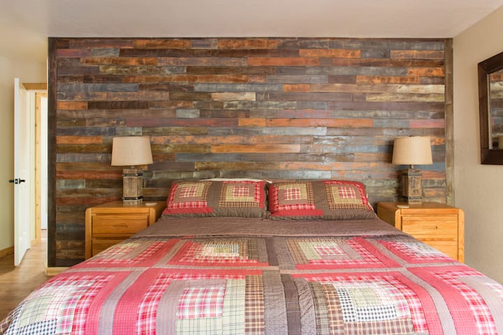 Dormitorio principal con cama «cal king» y pared de tablas de madera personalizada