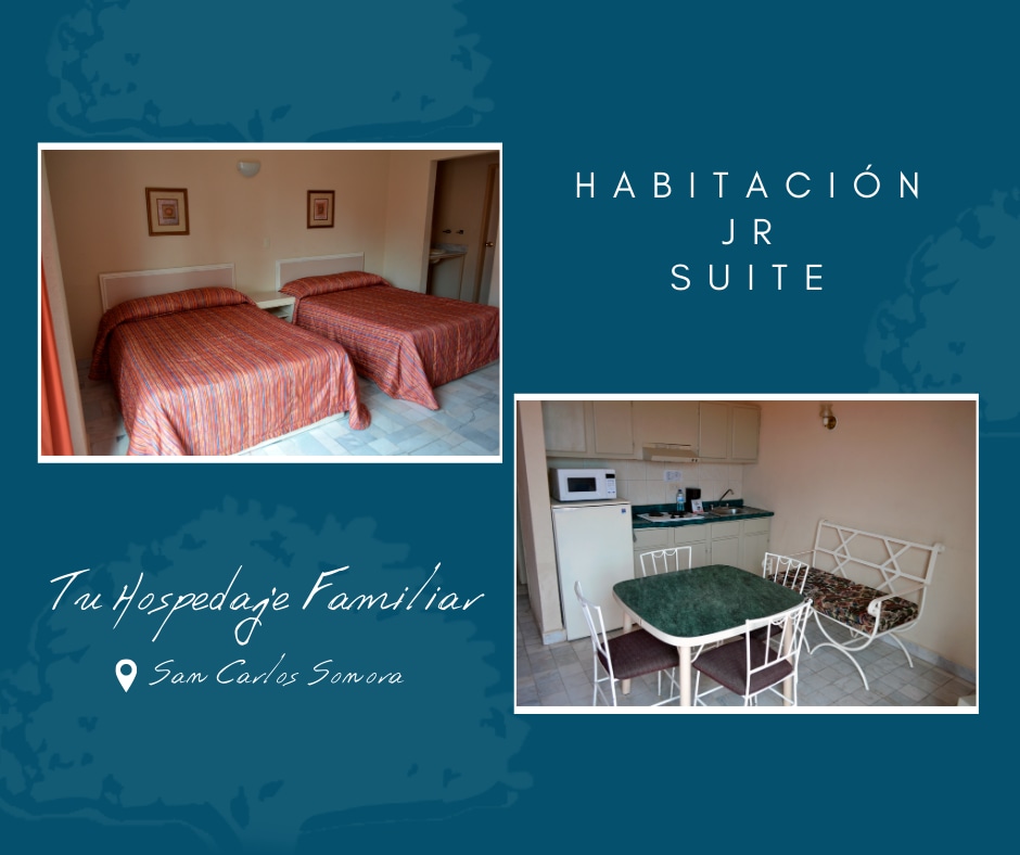 The room features two spacious beds covered in textured red and orange bedspreads. A small kitchenette area is visible, alongside a dining table with four chairs, creating a family-friendly seating arrangement.