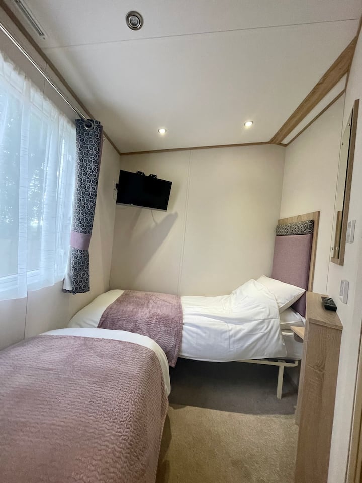 La chambre à deux lits dispose de beaucoup d'espace entre les lits et une télévision connectée.