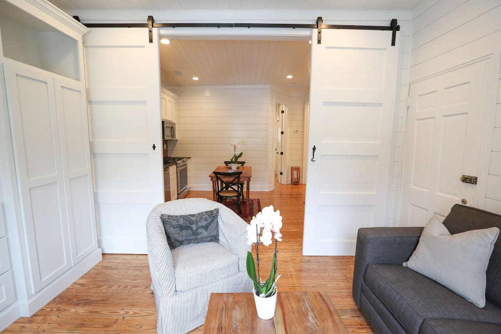 Extra-tall vintage barn doors slide all the way open to create a large open-concept living area flowing into the kitchen and foyer.