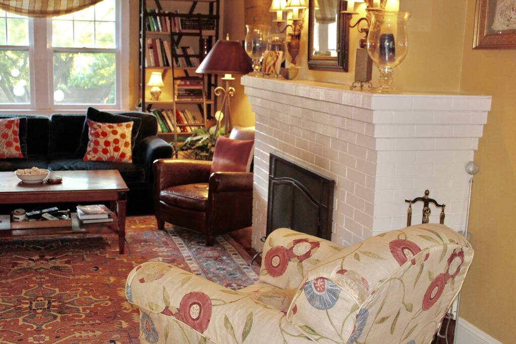 A comfortable social space with ceiling fans, sunny window views, and a wood-burning fireplace.