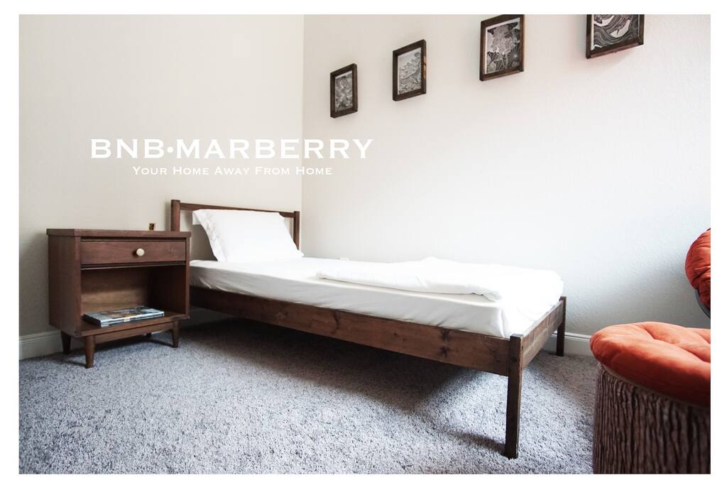 Single bed in a private room with a pretty antique nightstand.