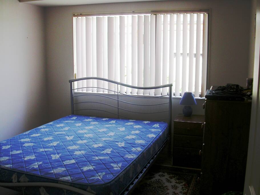 The double bedroom, showing the Queen bed, bedside drawers, lamp and chest of drawers.