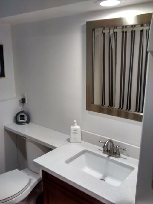 Private 3/4 bath with quartz counter top and tile floor.