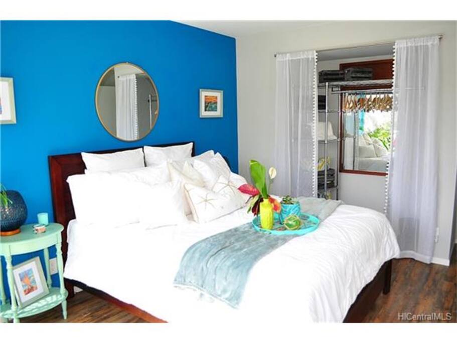 Angle of the 1st bedroom from the floor to ceiling windows. Closet is well-organized with storage racks, hangars, and mirror.
