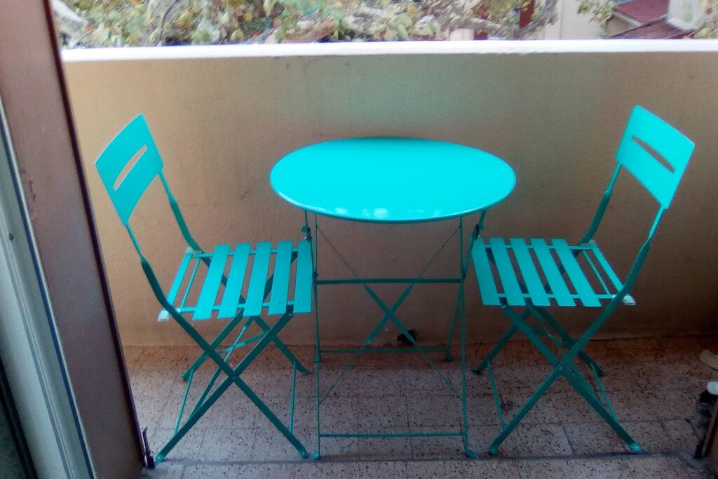 balcon avec petite table ronde de bistrot et deux chaises pliantes