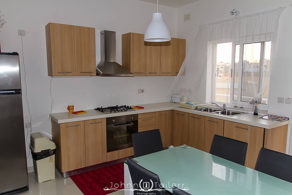 Modern kitchen with microwave and gas oven, dish washer and large fridge.