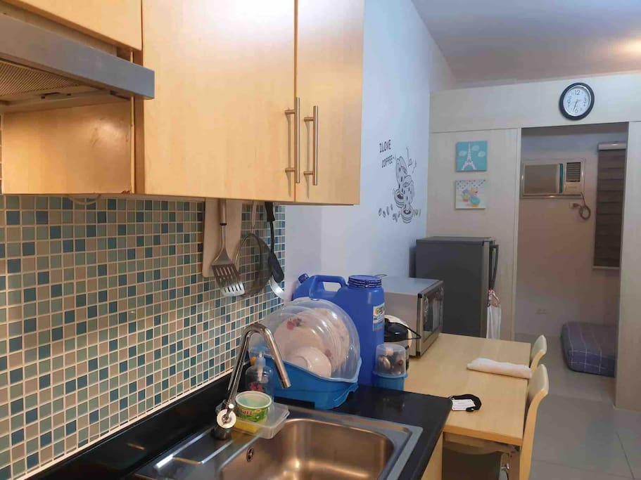 Kitchen area, electric stove w/ exhaust, microwave and refrigerator, rice cooker, pots and pans