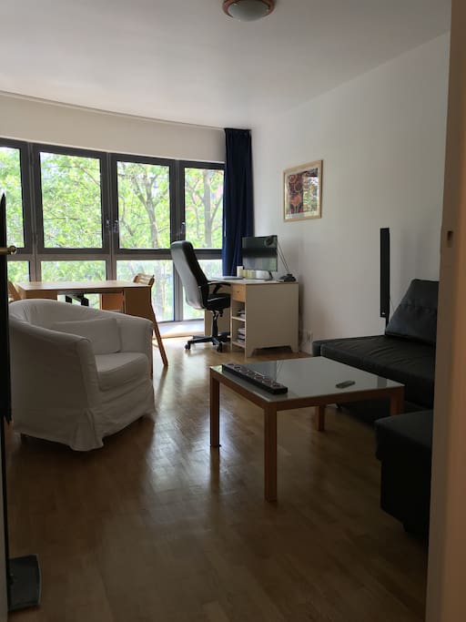 Large living room with bow window in the trees.