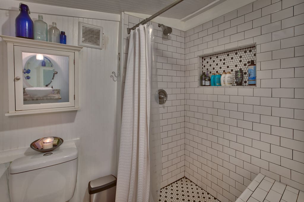 Full bath with walk-in tiled shower with bench seating