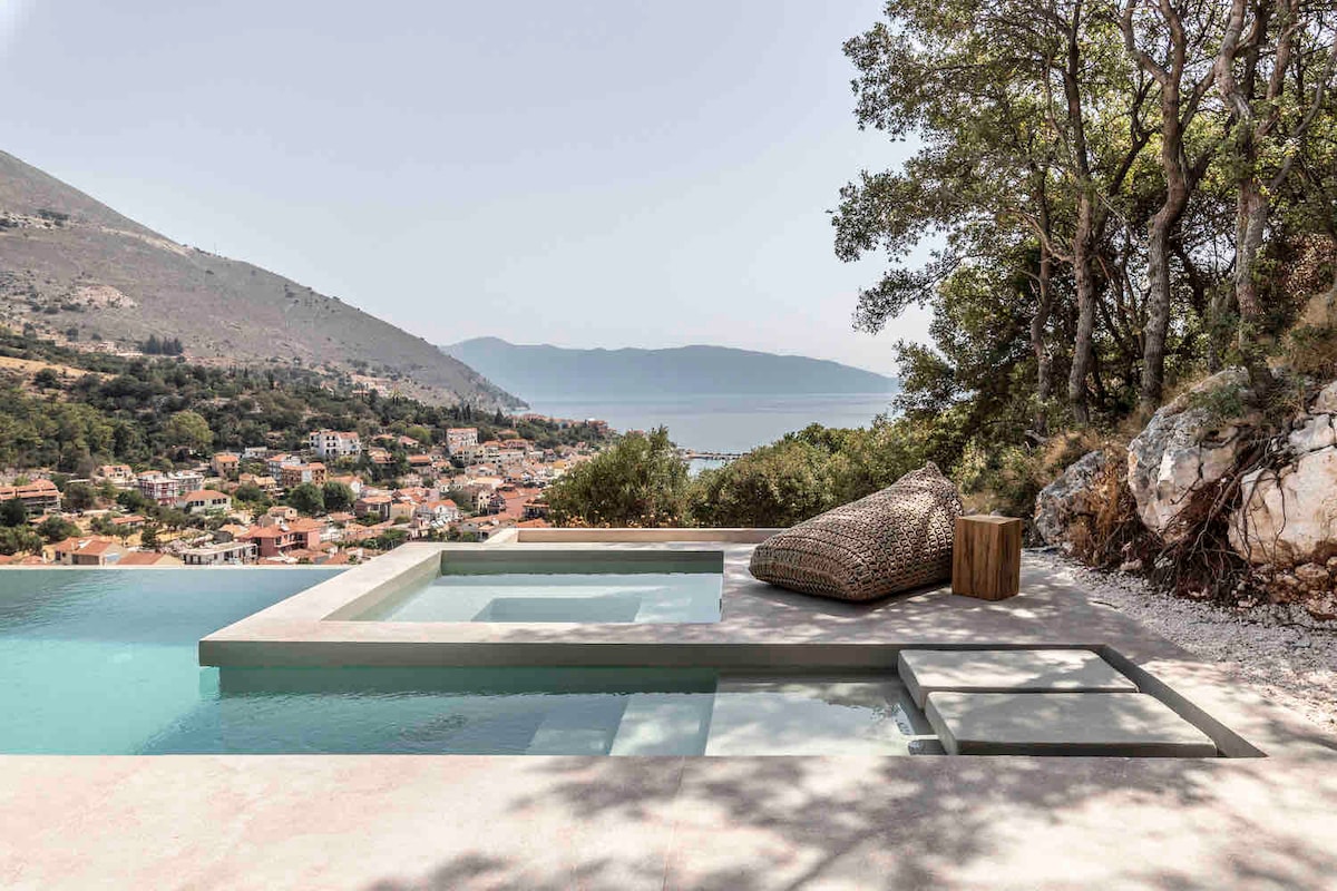 The outdoor area features a private swimming pool complemented by a jacuzzi. A textured lounge chair is positioned nearby, with a scenic view of the surrounding landscape visible in the background, showcasing hills and distant water.