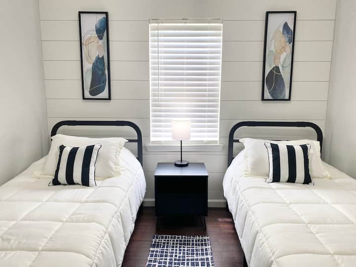 There are two twin beds in this guest room with a night stand and table lamp that has USB ports