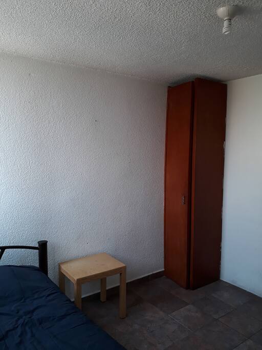 La recámara cuenta con cama, una mesita de centro y repisas.