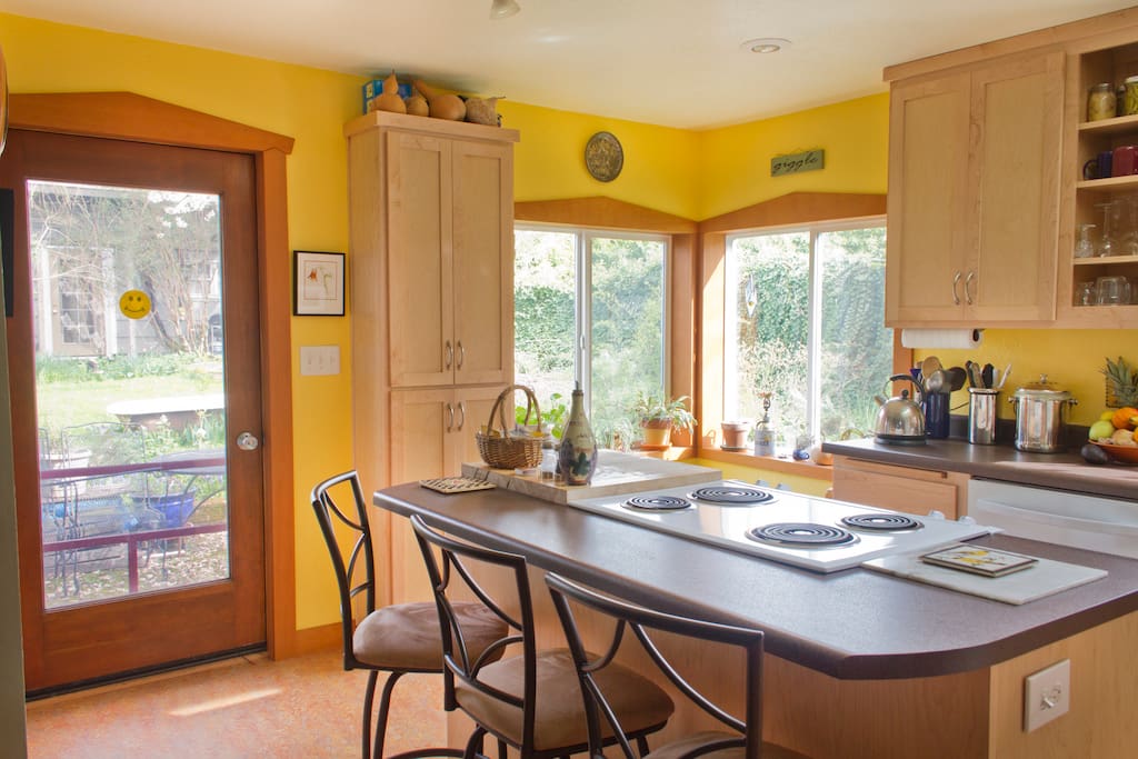 Sunny kitchen with island cooking area, dishwasher, and view of garden and bee hive