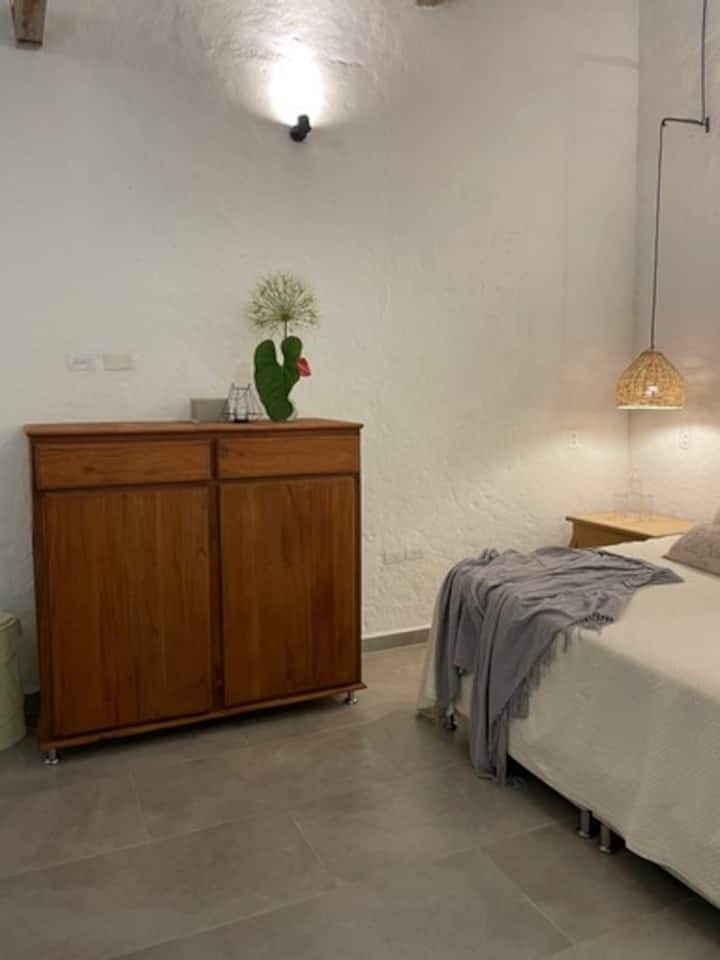 Chambre confortable, éclairage chaleureux et décoration dans des tons neutres. Il dispose de lampes suspendues en osier. Idéale pour repos et calme.