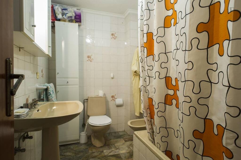 Baño dotado con lo indispensable: váter, bañera, bidé, lavabo y muebles de baño.