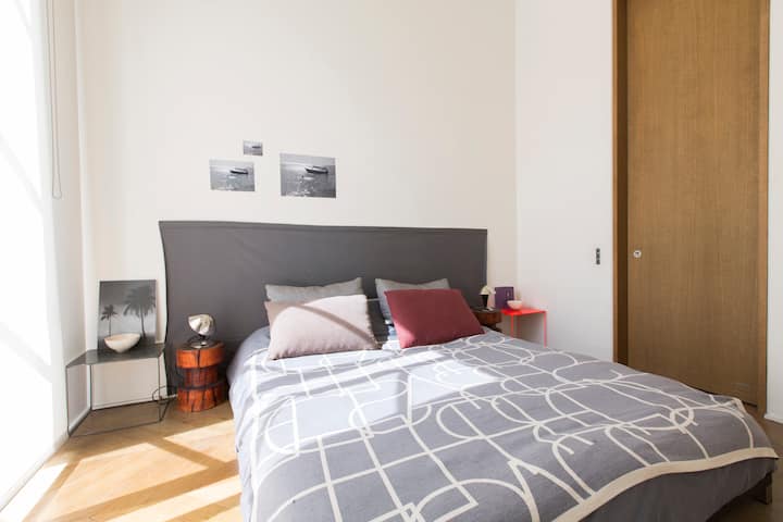Dormitorio soleado y tranquilo con una cama tamaño queen de 160x200, baño privado. El dormitorio tiene una ventana alta frente al patio.
El dormitorio tiene una ventana alta frente al patio con persianas de madera para pasar la noche y una persiana enrollable para la luz del sol.