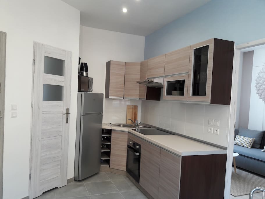 Une cuisine bien equipé avec un frigo, un plaque de cuisson, un four, un micro-onde, un bouilloire, une cafétiere, un pain grille, une lave-vaisselle, un lave-linge, des vaisselles, des casseroles, etc.