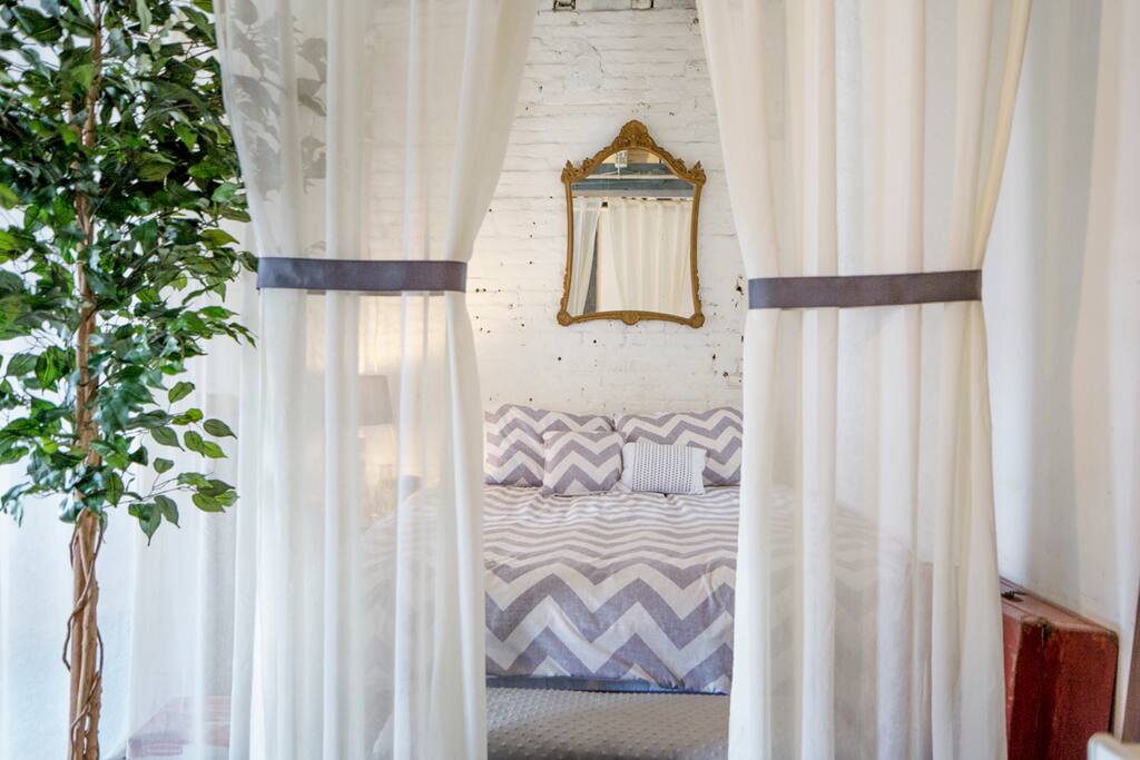 The queen sized bed with feather mattress topping and whimsical sheers hanging via invisible cords to create a sleeping oasis.