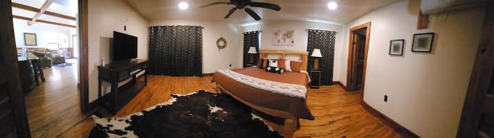 חדר שינה ראשי ענק עם אמבטיה פרטית, טלוויזיה ומאוורר תקרה. 