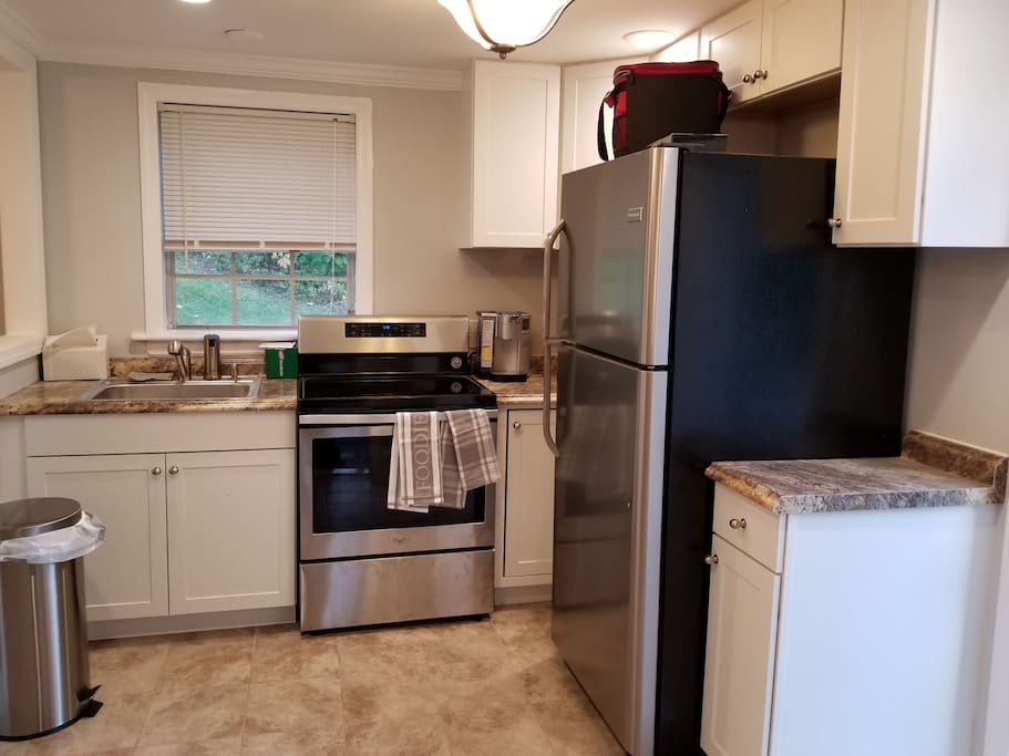 New kitchen with stainless steel appliances. Dishes, glasses, pans, silverware, toaster oven and coffee pot