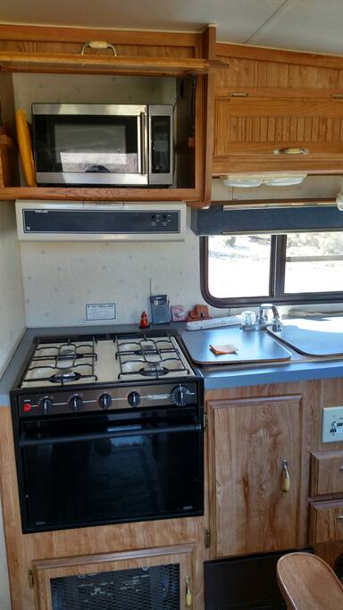 4 burner stove, oven, microwave, and double sink in kitchen
