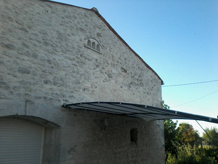 Façade avec tonnelle et salon de jardin /barbecue