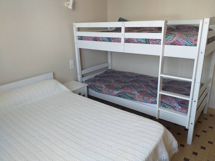 Un dormitorio con una cama de 140 y dos literas y un armario