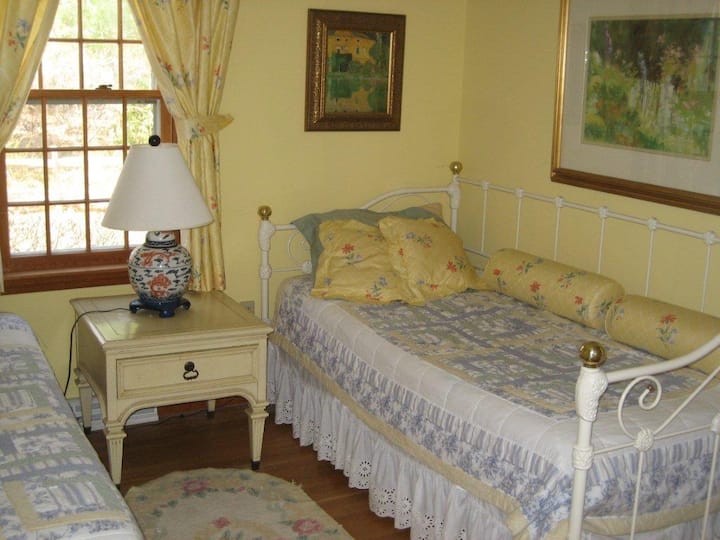 Dva odvojena kreveta u osunčanoj žutoj spavaćoj sobi