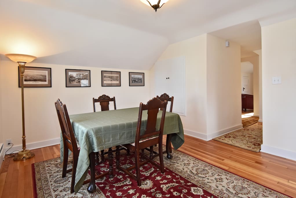 Formal dining room with seating for 4. Antique furnishings and historic photographs of Seattle at the turn of the century