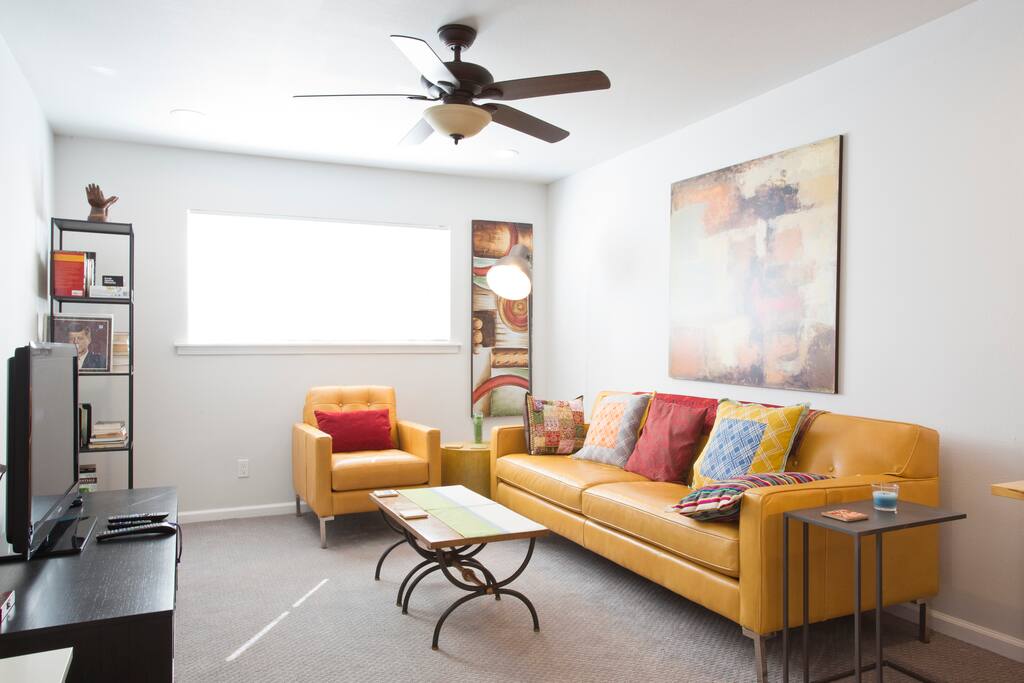 Large living room with leather couch and chair, HD TV (with Roku) and computer desk with monitor.