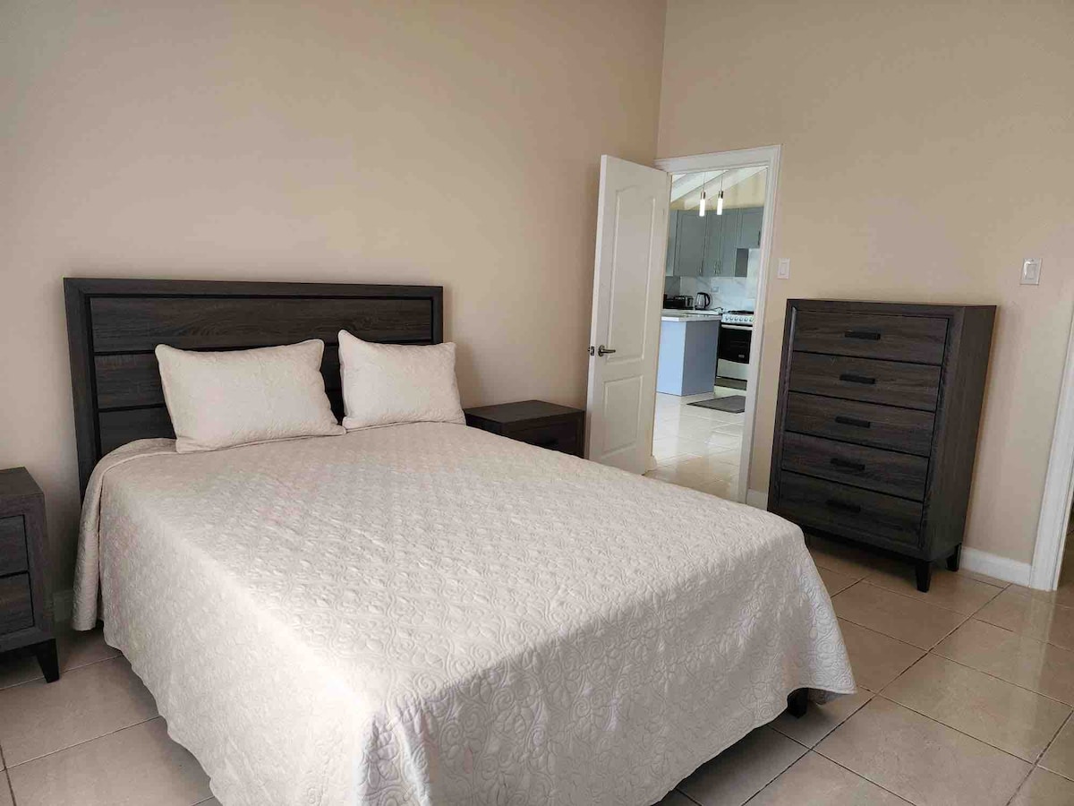 1号卧室配有标准双人床、床头柜和梳妆台，还有空调，从卧室到卫生间的门 