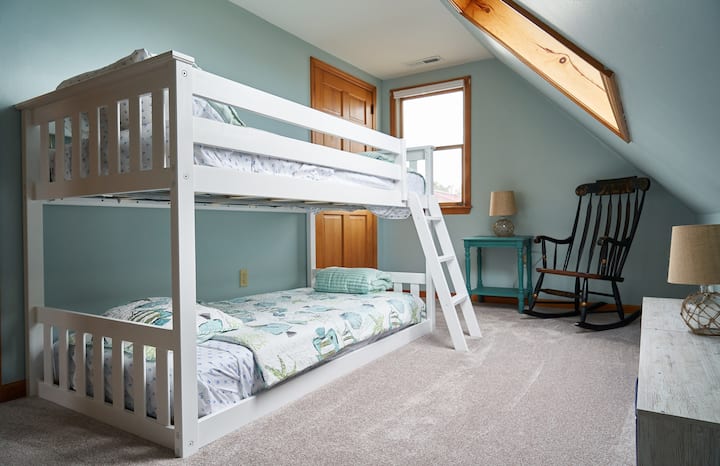 Кревет во кревет со поглед на помала/наклонета линија на покривот/таванот на таванот. Плакар со полици.