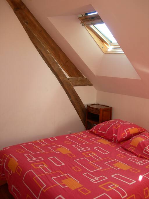 Lit double, deux tables de chevet, un velux et une fenêtre