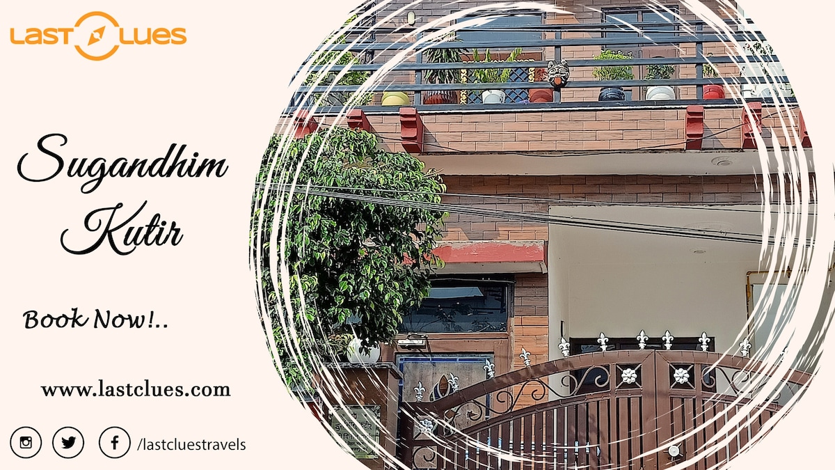 The exterior of a charming building is displayed, showcasing a balcony adorned with potted plants. A decorative gate leads into the property surrounded by greenery, while warm tones of the brick facade create an inviting appearance.
